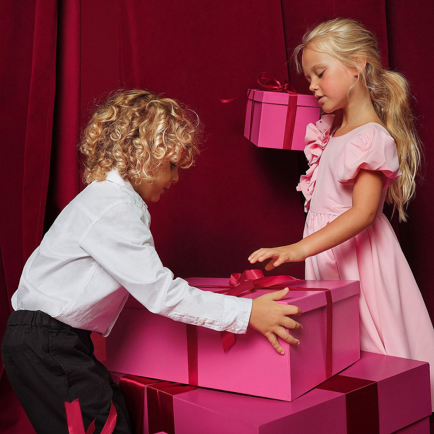 Un bambino e una bambina giocano con delle scatole regalo. 