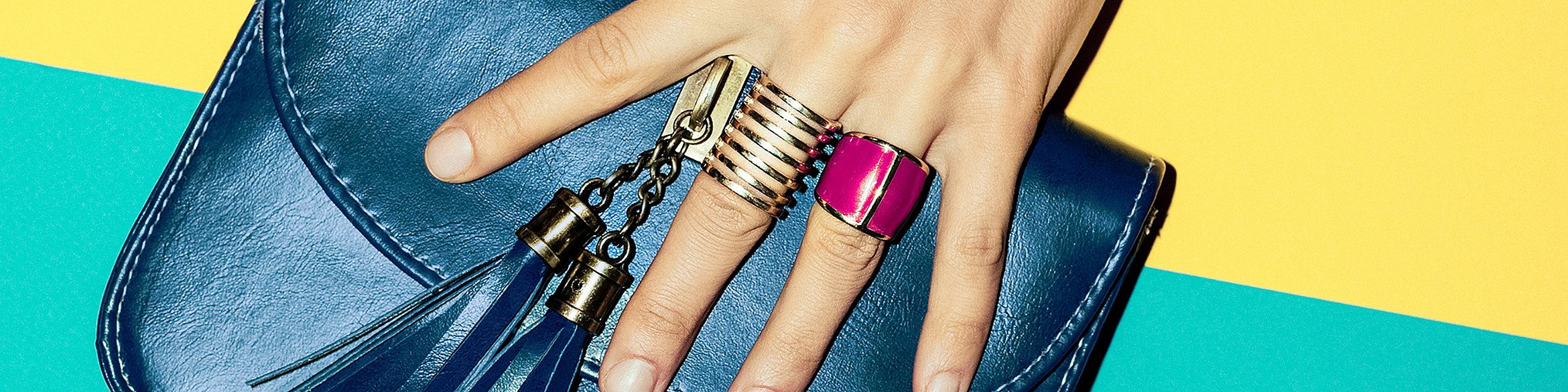 L'immagine mostra delle dita che reggono una borsetta.