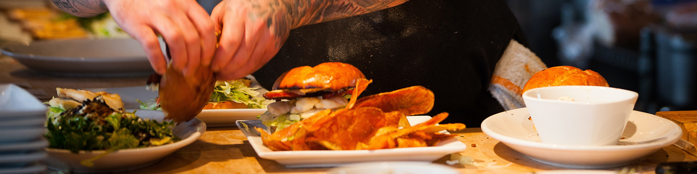 L'immagine mostra un piatto pieno di insalata, un altro piatto con hamburger e patatine e un piatto fondo.